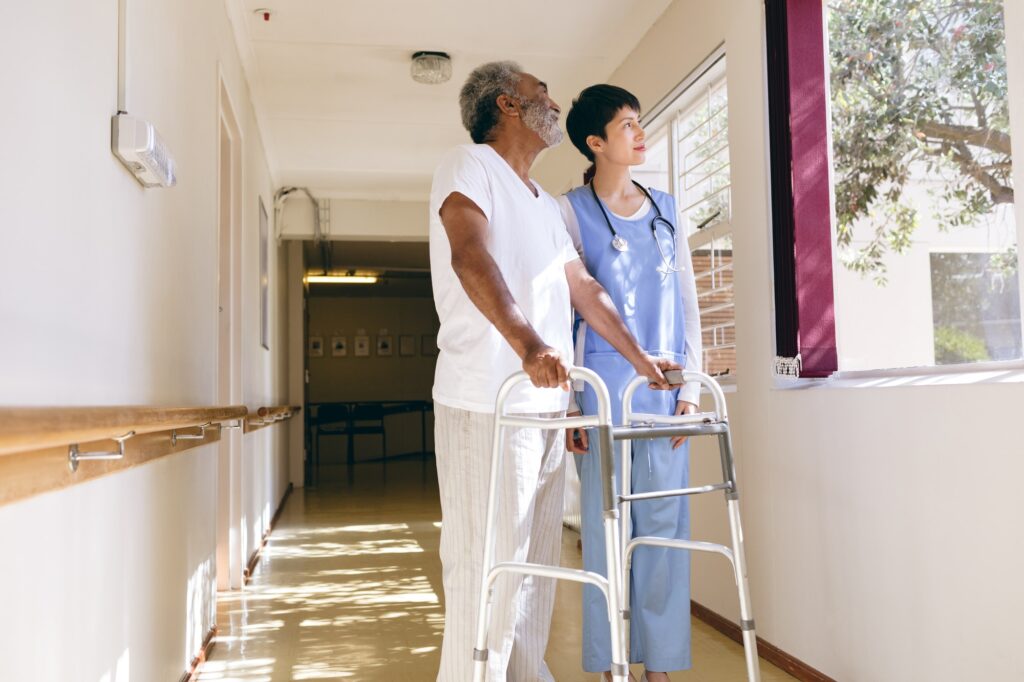 Female nurse and senior male patient interacting with each other in the retirement home