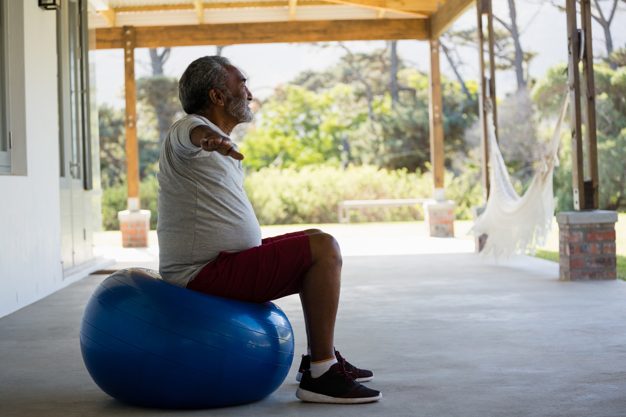 Senior man exercising on exercise ball in the porch